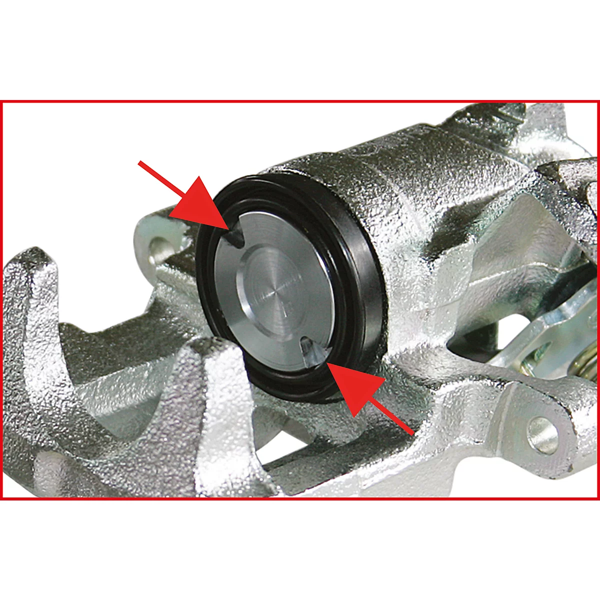 Nahaufnahme eines Bremssattels mit zwei roten Pfeilen, die auf das Innere des Bremssattels zeigen.